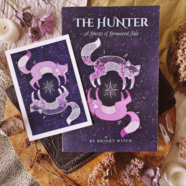 Photograph of The Hunter novelette and corresponding mini art print. Cover and art illustrations feature two ethereal foxes encircling a silver star.